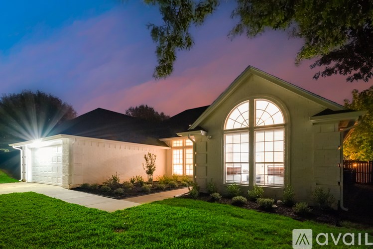 A house with a well-lit front yard and a large arched window.