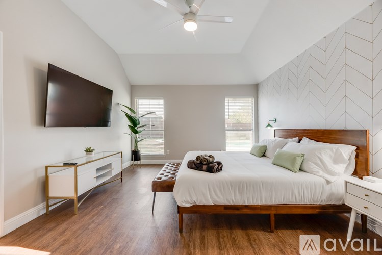 A bedroom with a large bed and a flat screen TV mounted on the wall.