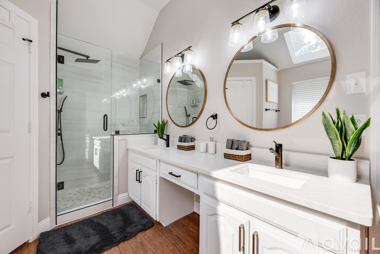 A bathroom with a white vanity and a round mirror above it.
