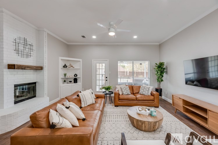 A living room with a brown leather couch and a fireplace.