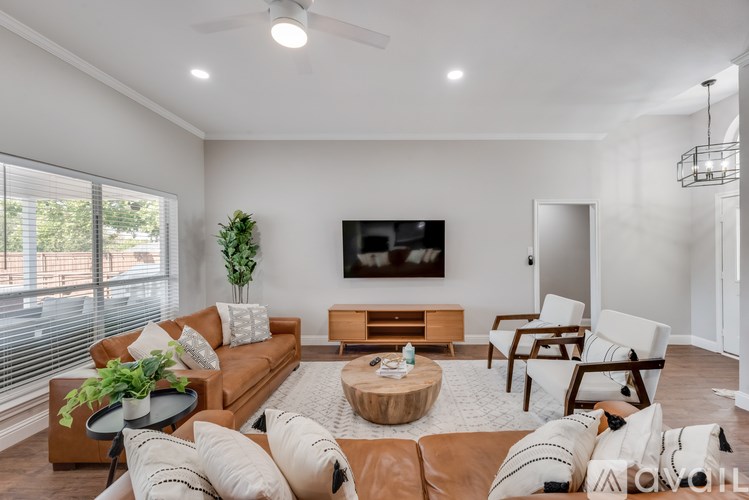A living room with a brown couch, a coffee table, and a flat screen TV mounted on the wall.
