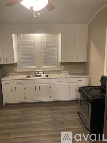 A kitchen with white cabinets and a black stove top oven.