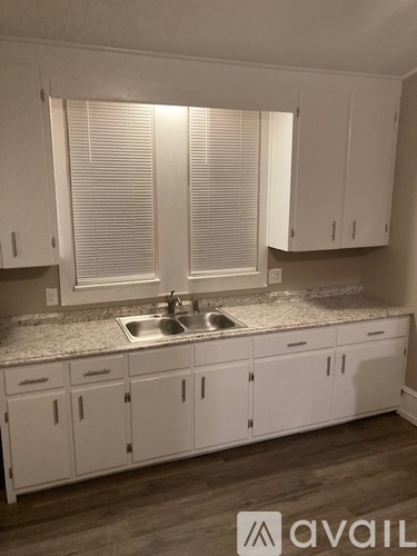 A kitchen with white cabinets and a granite countertop.