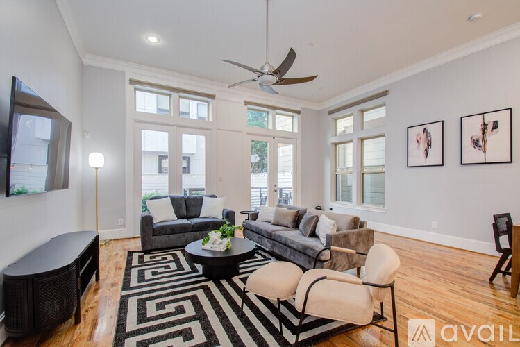 A living room with a black and white rug and a grey couch.