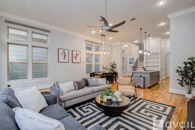 A living room with a grey couch and a black and white rug.