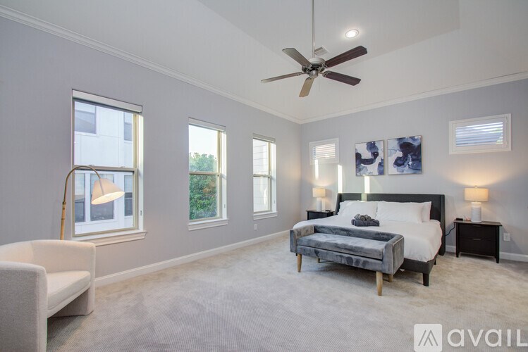 A bedroom with a large bed, a chair, and a ceiling fan.