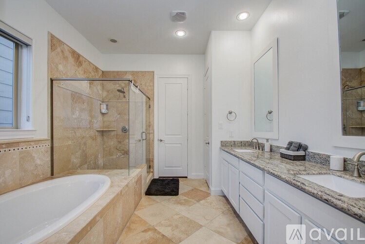 A bathroom with a tub, sink, mirror, and a door.