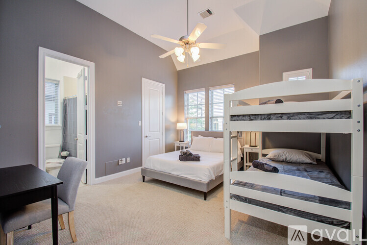 A bedroom with a white bunk bed and a single bed with a ceiling fan.