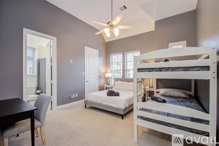 A bedroom with a white bunk bed and a single bed with a ceiling fan.