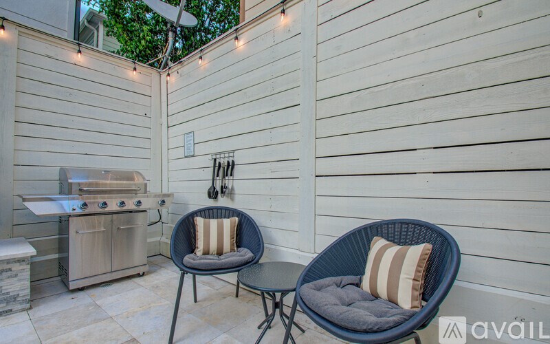 A patio with a grill and two chairs.