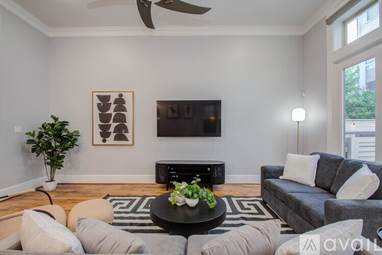 A living room with a grey couch, a black coffee table, and a television mounted on the wall.