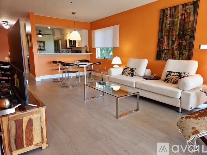 A living room with a white couch, a glass coffee table, and a television.