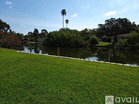 A grassy area with a body of water and trees in the background.