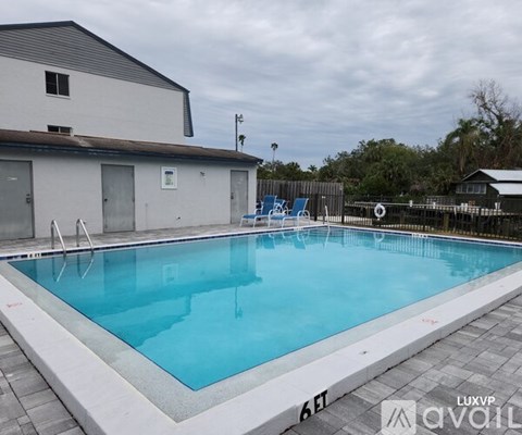A large outdoor swimming pool with a white building in the background.