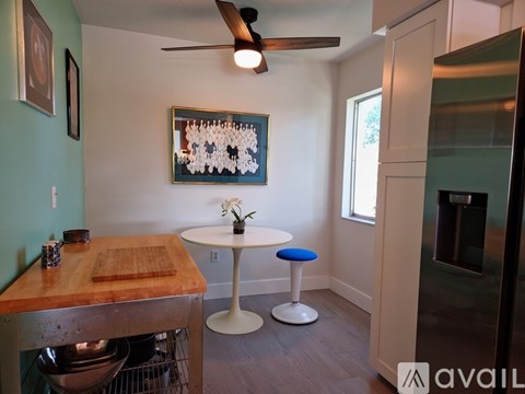 A kitchen with a table and a ceiling fan.