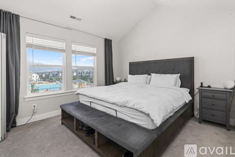 A bedroom with a large bed, a nightstand, and a window overlooking a pool.