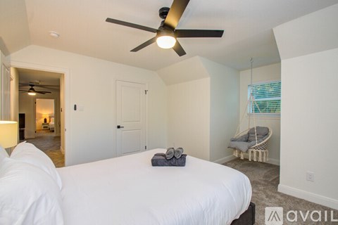 A bedroom with a white bed and a ceiling fan.