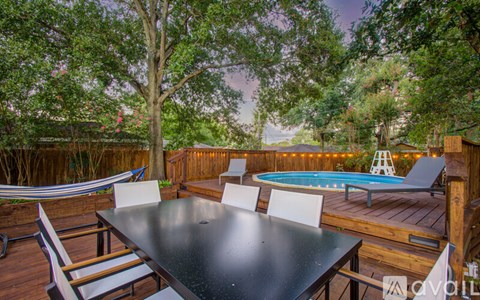 A backyard with a table and chairs and a pool.