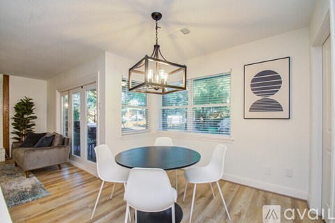 A dining room with a round table and white chairs.