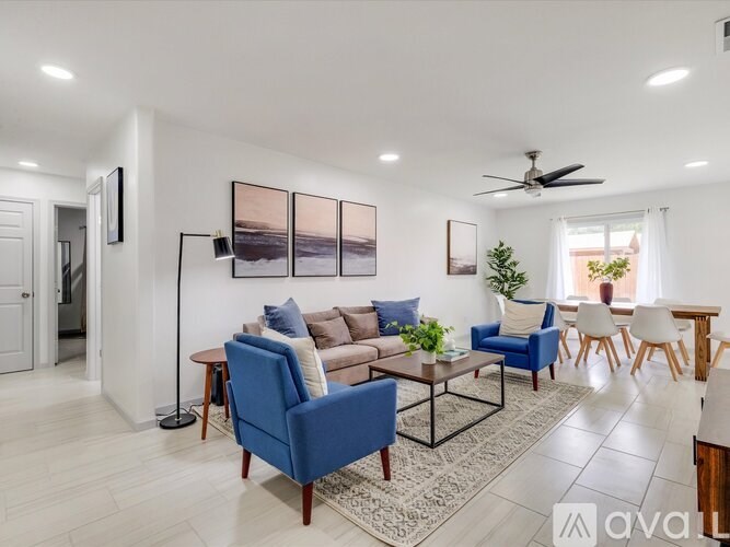 A living room with a blue sofa, a brown couch, a coffee table, and a ceiling fan.