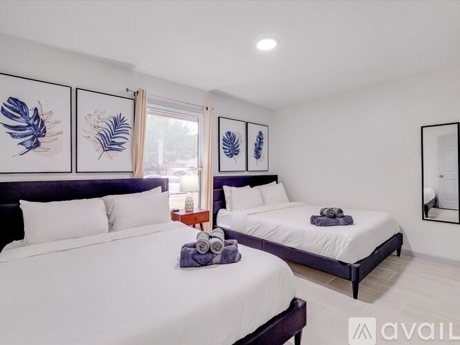 A bedroom with two beds, one with a purple headboard, and a mirror on the wall.