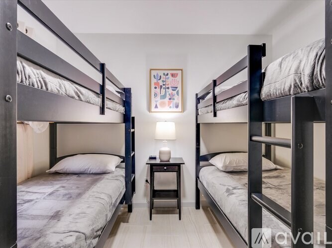 A room with two bunk beds and a small table in between them.