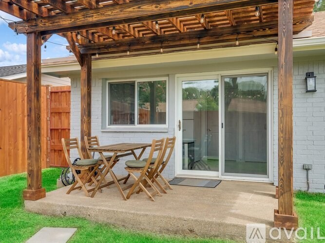 A wooden patio with a table and chairs is in front of a house.