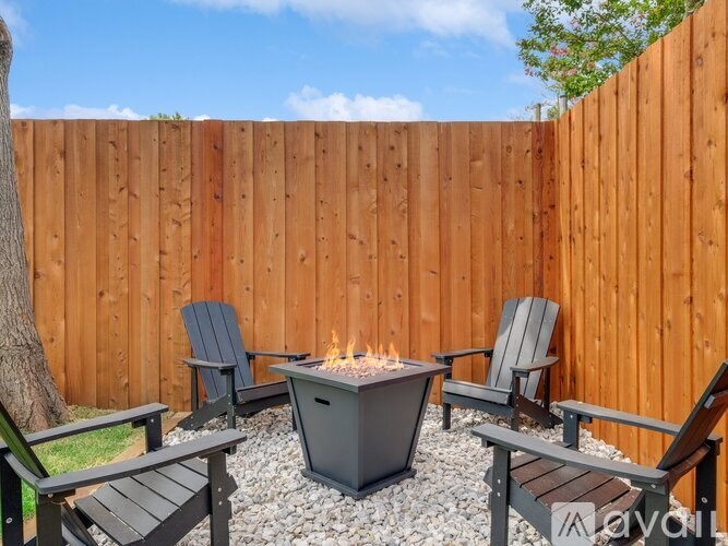 A backyard with a fire pit and chairs.