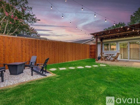 A backyard with a wooden fence, a hot tub, and a patio area.