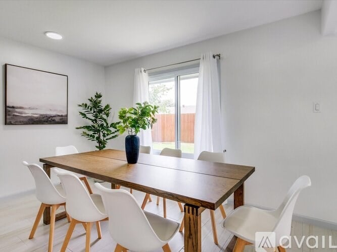 A dining room with a wooden table and white chairs.
