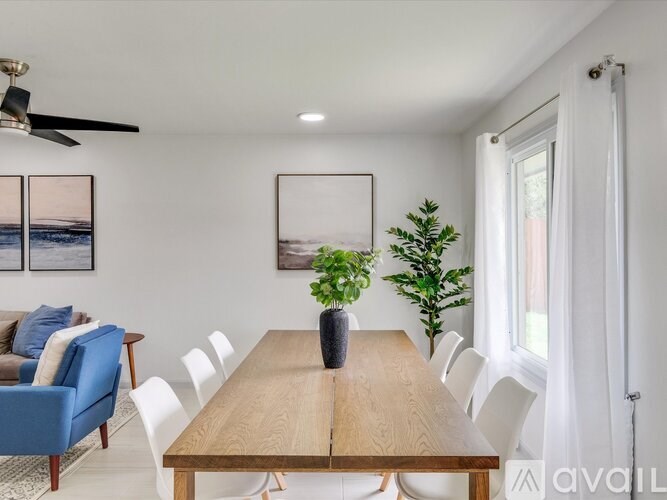 A dining room with a wooden table and white chairs.