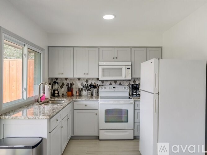 A kitchen with white appliances and cabinets.