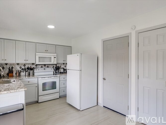 A kitchen with white appliances and cabinets.