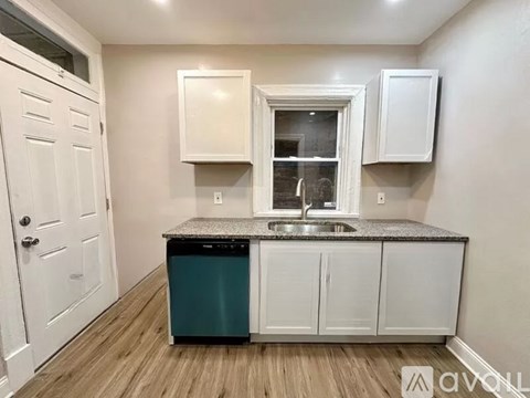 A kitchen with a white door, a window with white frames, and a granite countertop.