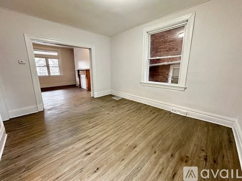 A room with wooden flooring and a window with blinds.