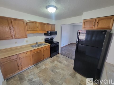 A kitchen with wooden cabinets and a black refrigerator.