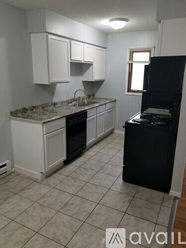 A kitchen with white cabinets and a black fridge.