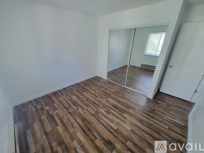 A room with wooden flooring and white walls.
