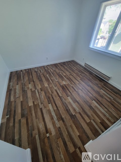 A room with wooden flooring and white walls.