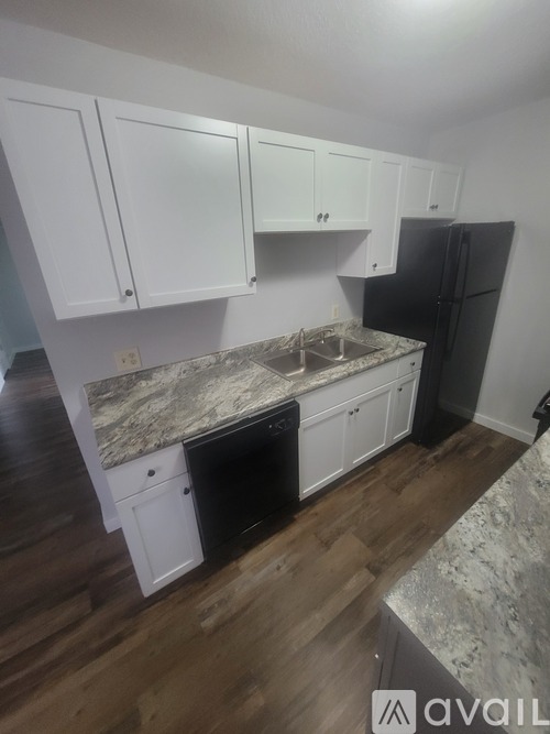 A room with wooden flooring and a kitchenette.