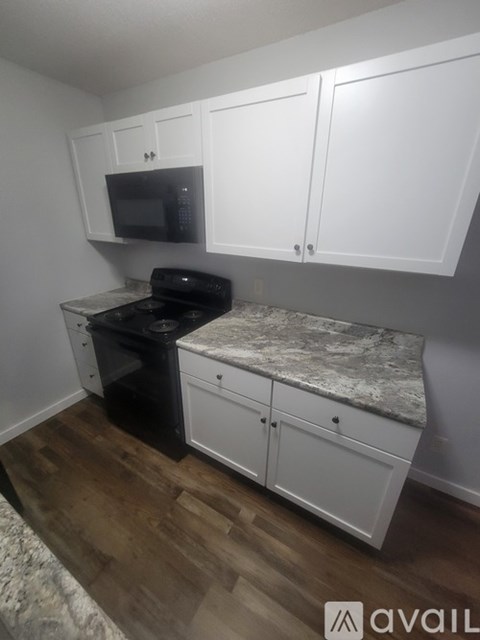A kitchen with white cabinets and a black microwave.