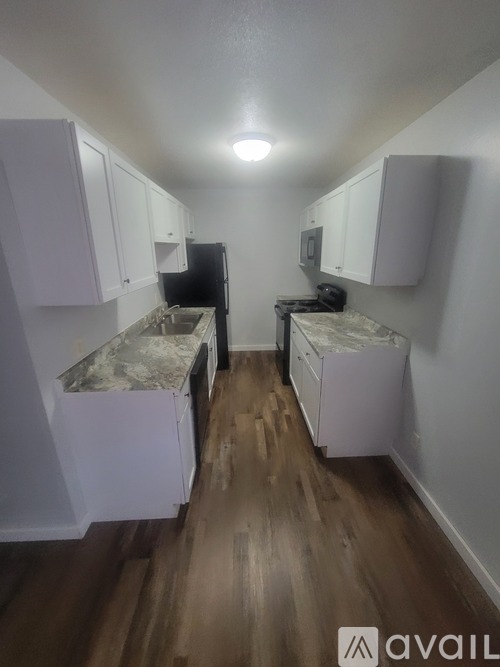 A kitchen with white cabinets and a wooden floor.