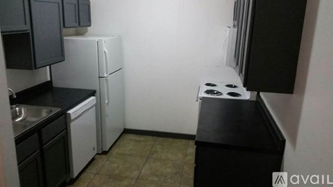 A kitchen with black cabinets and a white fridge.