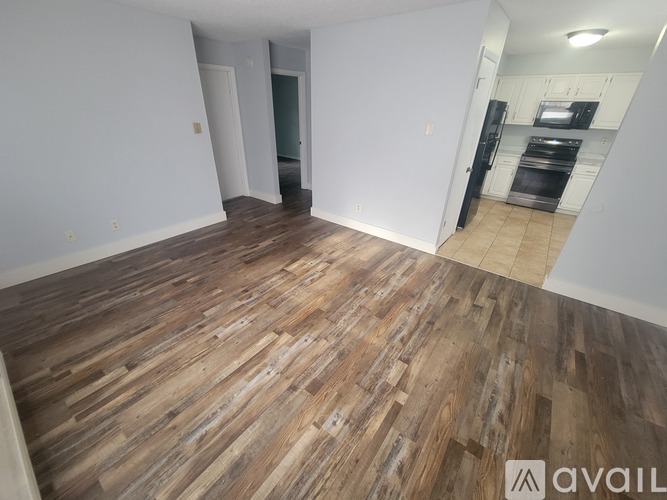 A kitchen with white appliances and wooden floors.