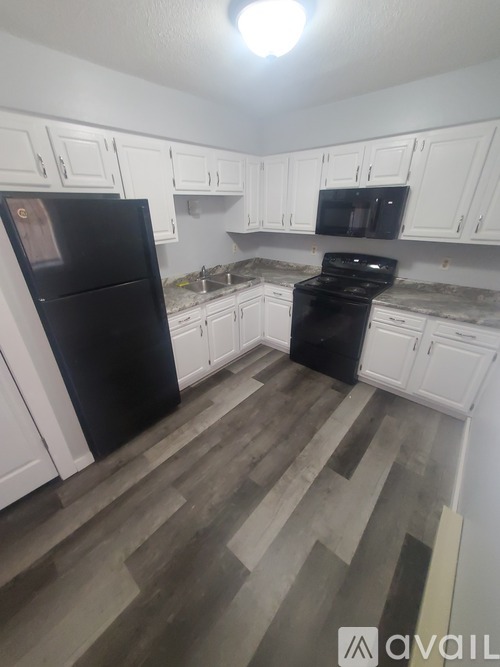A kitchen with black appliances and white cabinets.