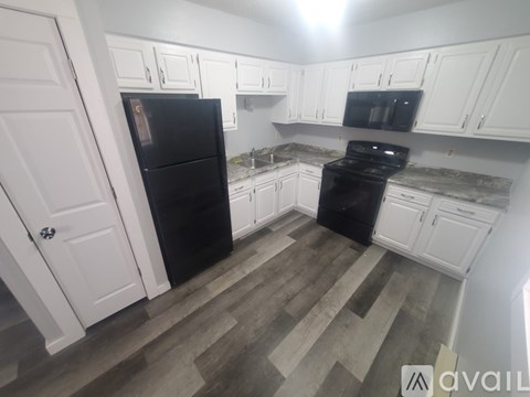 A kitchen with black appliances and white cabinets.