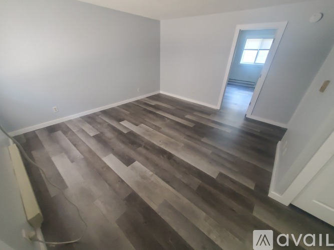 A room with wooden flooring and a doorway leading to another room.
