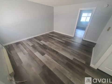 A room with wooden flooring and a doorway leading to another room.
