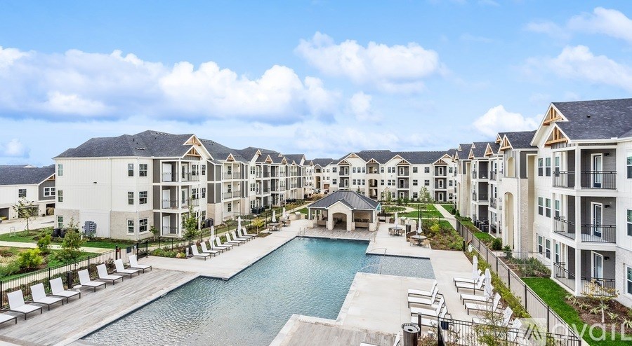 A large, modern apartment complex with a pool in the foreground.