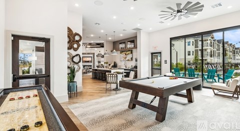 A billiard table is in the middle of a room with a pool table and a foosball table.